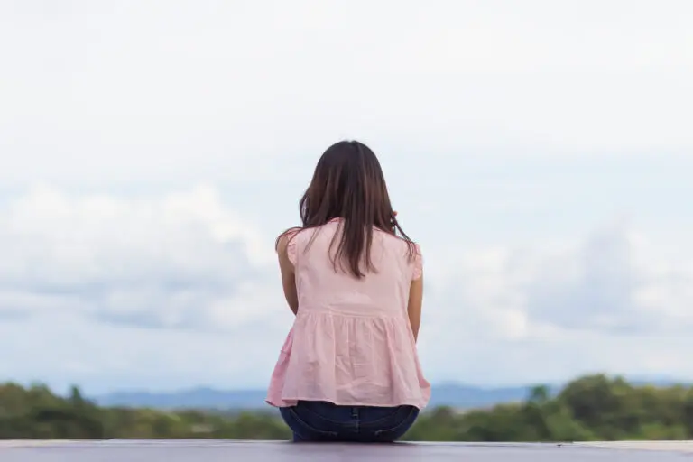 The Loneliness Epidemic a woman sitting on a ledge looking at the sky