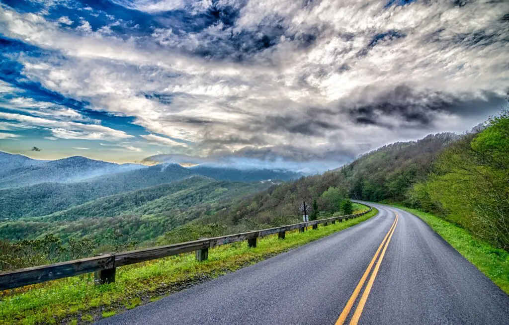 a road with trees and mountains in the background