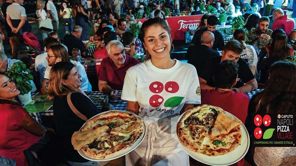 a woman holding two plates of pizza